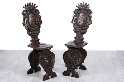 Lot 93 - An ornate pair of 19th Century Italian Renaissance revival carved oak Scabello hall chairs