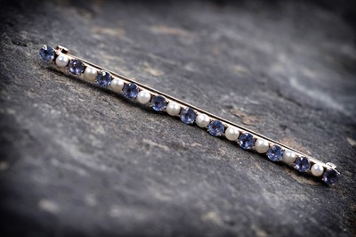 Lot 253 - An early 20th Century sapphire and seed pearl bar brooch