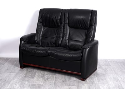 Lot 86 - A modern black leather two-seater reclining sofa