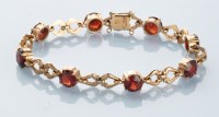 Lot 865 - A garnet and 9ct. yellow gold bracelet, by...