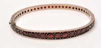 Lot 969 - A garnet bangle, set with graduated circular...