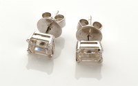 Lot 842 - A pair of diamond stud earrings, each emerald...